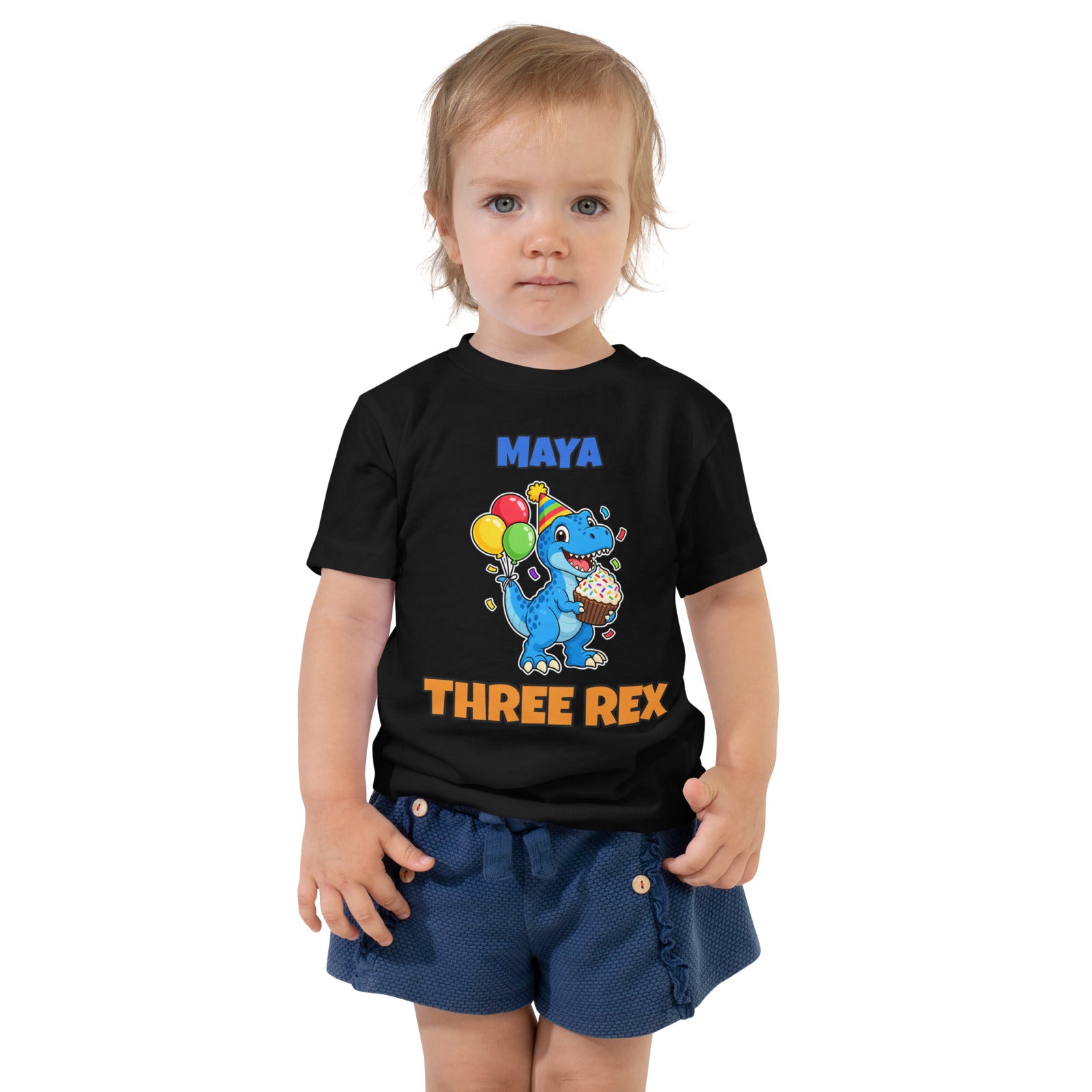 Birthday Rex personalized toddler dinosaur birthday t-shirt in Black, blue party-hat T-rex with cupcake and balloons between the name MAYA and THREE REX, worn by a child, front view
