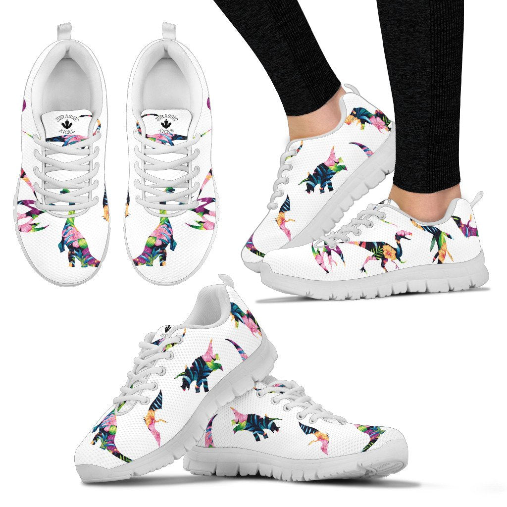 Woman wearing a paid of white dinosaur sneakers featuring vibrant floral patterns of all of your favorite dinosaurs on a white background. 
