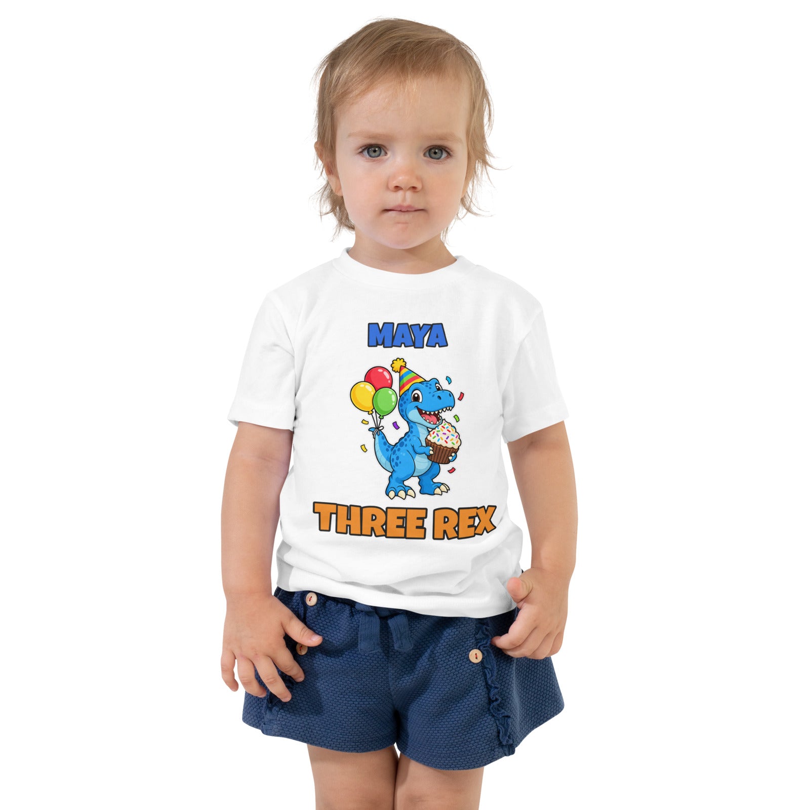 Birthday Rex personalized toddler dinosaur birthday t-shirt in White, blue party-hat T-rex with cupcake and balloons between the name MAYA and THREE REX, worn by a child, front view