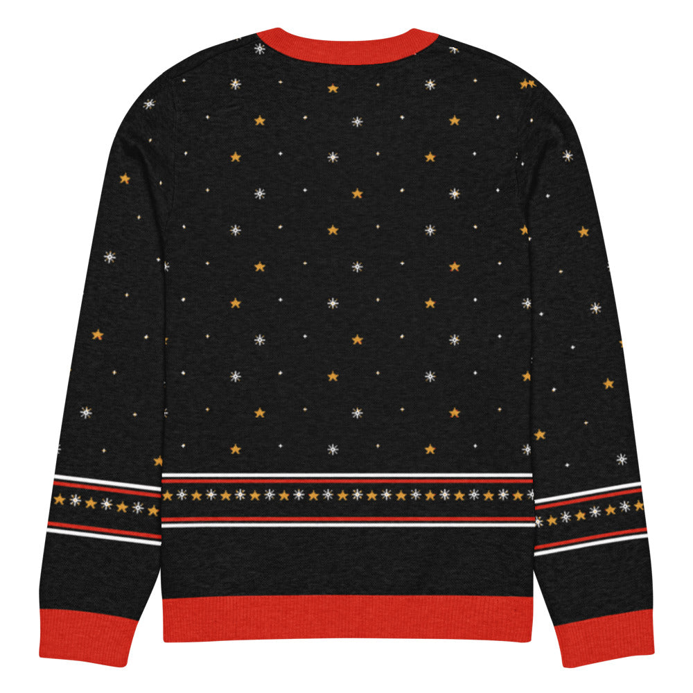Back of the black Pterodactyl Sleigh Ride knitted Christmas sweater with gold stars, snowflakes and a fair-isle star band above the red hem