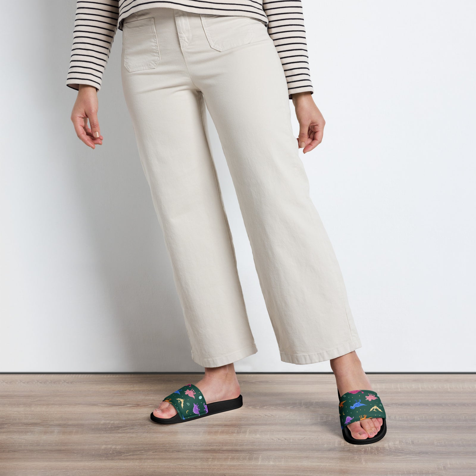 Woman wearing Emerald Jewel Dinos dinosaur slides with a jewel-tone dinosaur print strap