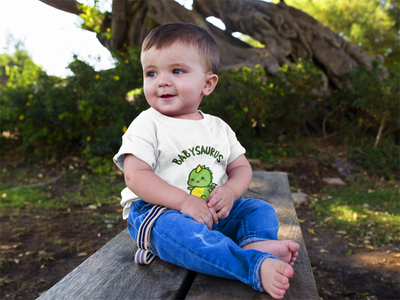 A baby wearing a t-shirt with a cute baby dinosaur titled Babysaurus. Perfect baby shower gift.