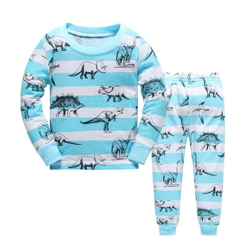 Light blue and white striped dinosaur pajamas for kids. Stenciled on top are T-Rex, Triceratops, Stegosaurus, and Brontosaurus's all over. 
